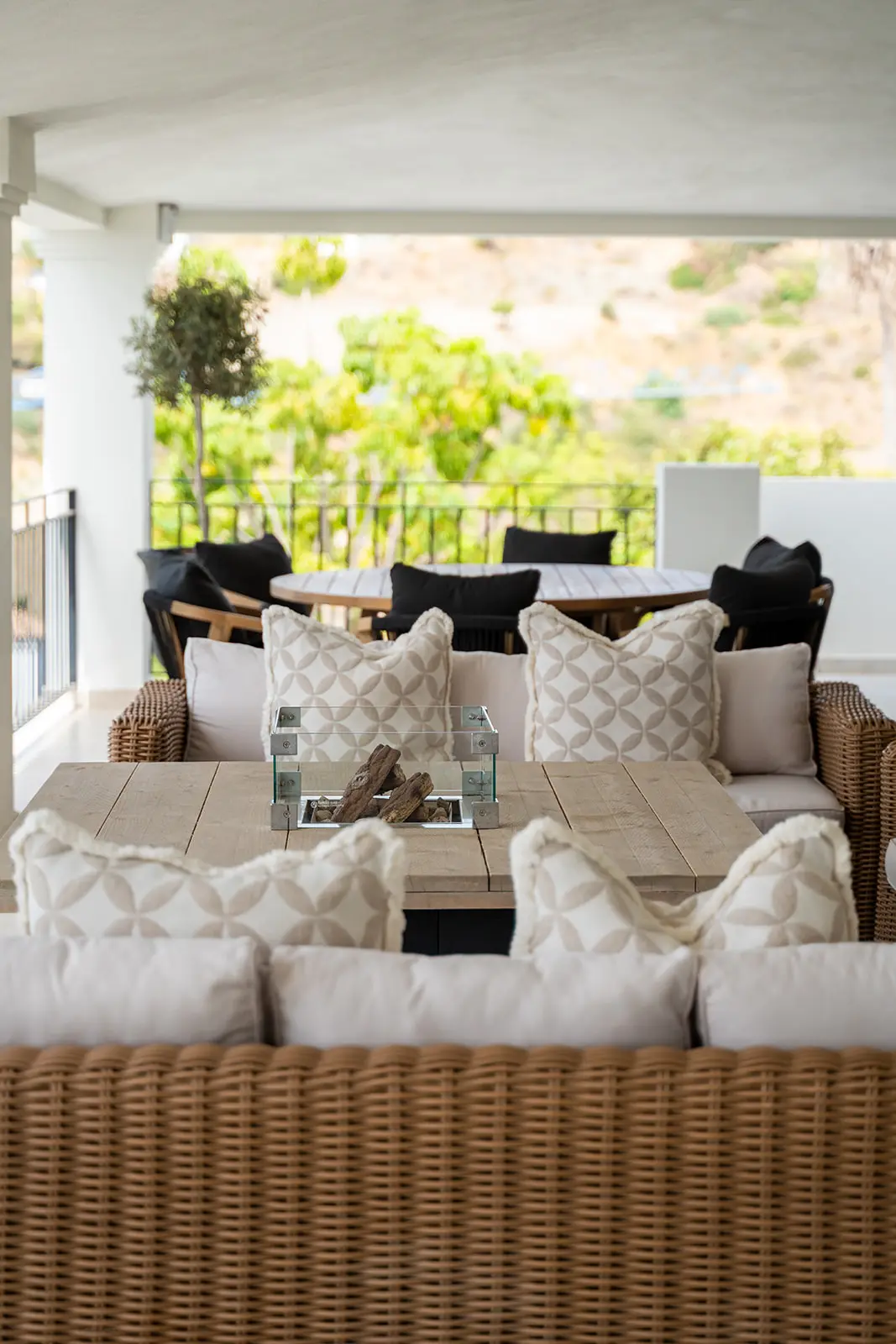 Covered terrace with woven lounge furniture looking out over the hills