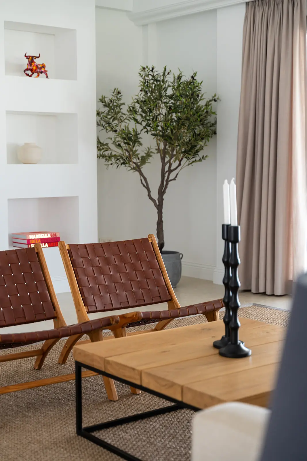 Sitting area with leather chairs and a potted olive tree beside the terrace doors