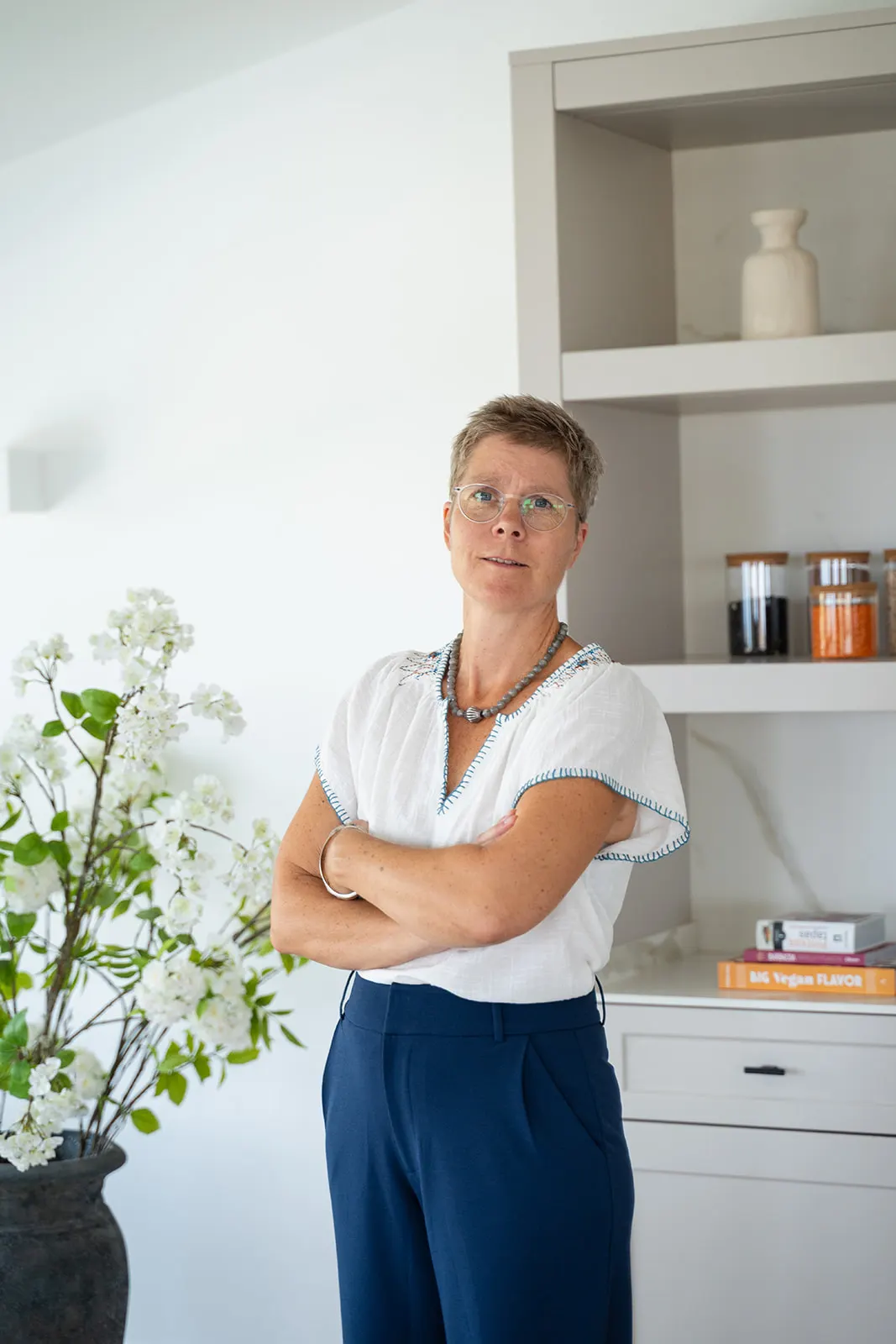 Portrait of Mette in a bright room with a vase of white blossom beside her
